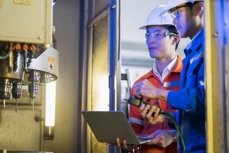 male asian engineer professional having discussion standing concult cnc machine factory two asian coworker brainstorm explaining solves process cnc operate machine